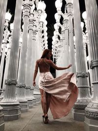 Rear view of woman walking amidst architectural column 