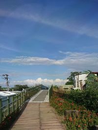 Empty footpath amidst buildings against sky