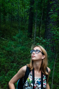 Portrait of young woman wearing sunglasses in forest