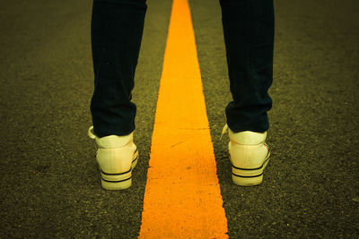 Low section of man standing on road
