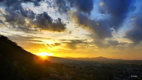 Sun shining through clouds over mountains