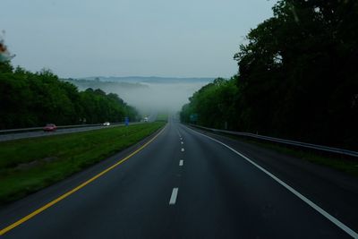 Road amidst trees against sky