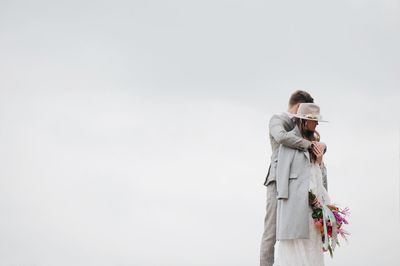 Bride and bridegroom standing against clear sky