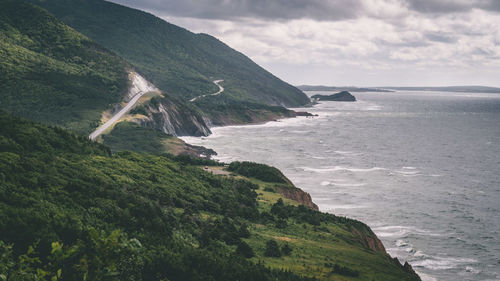 Scenic view of sea by mountains against sky