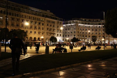 People on street amidst buildings in city at night