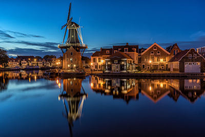 De adriaan windmill by river and houses at dusk