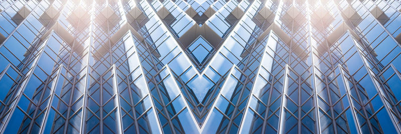 Full frame shot of modern glass building against blue sky