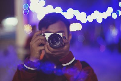 Young man photographing from camera at night