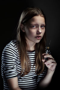 Portrait of beautiful young woman standing against black background