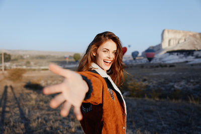 Portrait of young woman standing against mountain