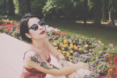 Portrait of woman wearing sunglasses against flowers