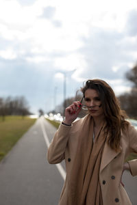 Young woman using mobile phone while standing on car