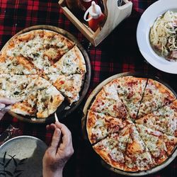 High angle view of hand holding pizza on table