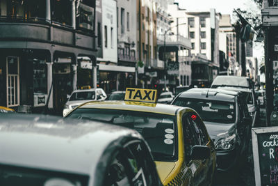 Taxi in traffic on road amidst buildings