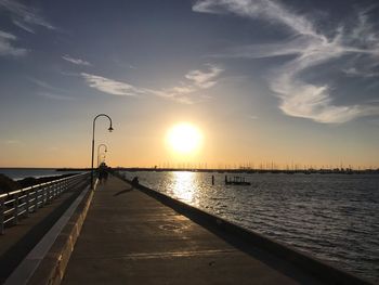 Pier over sea against sky during sunset