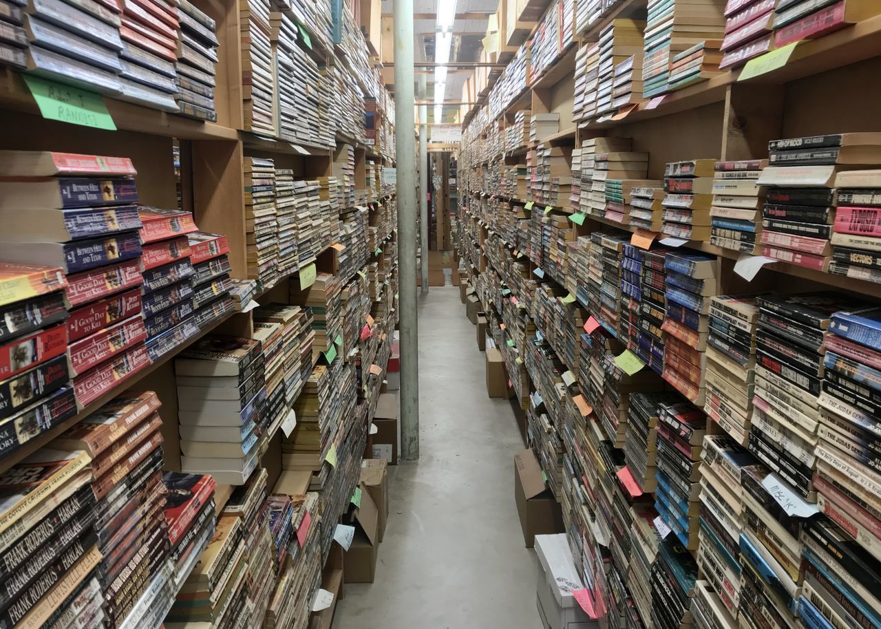 STACK OF BOOKS ON SHELF IN LIBRARY