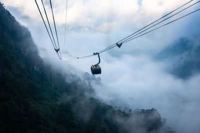 Low angle view of overhead cable car against sky