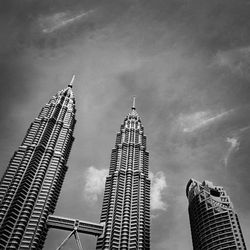 Low angle view of skyscrapers against cloudy sky