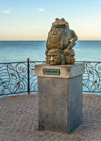 Statue by sea against sky