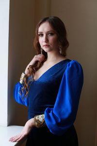 Teenage girl wearing royal blue dress standing at home