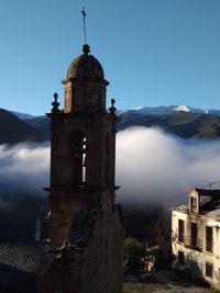 Historic building against clear blue sky during foggy weather