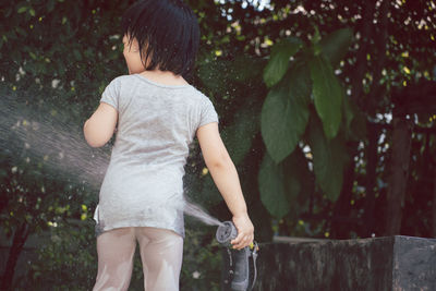 Rear view of boy standing by plants