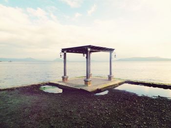 Gazebo against river and cloudy sky