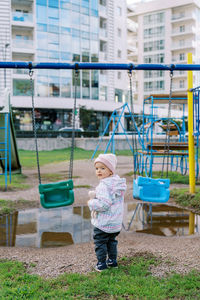 Rear view of boy swinging in playground