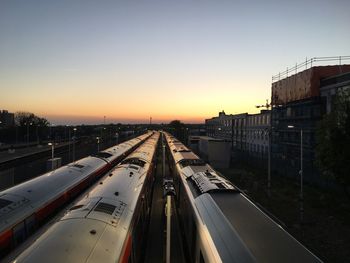 Railroad tracks in city against clear sky during sunset