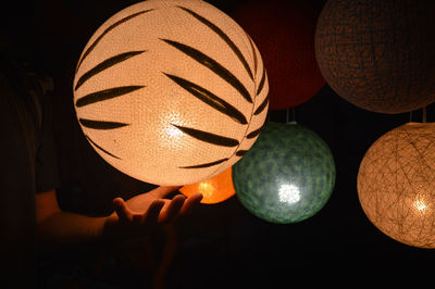 Close-up of hand under illuminated lantern in darkroom