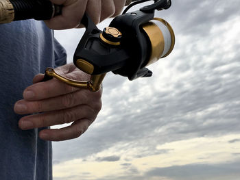 Low angle view of cropped hand against sky