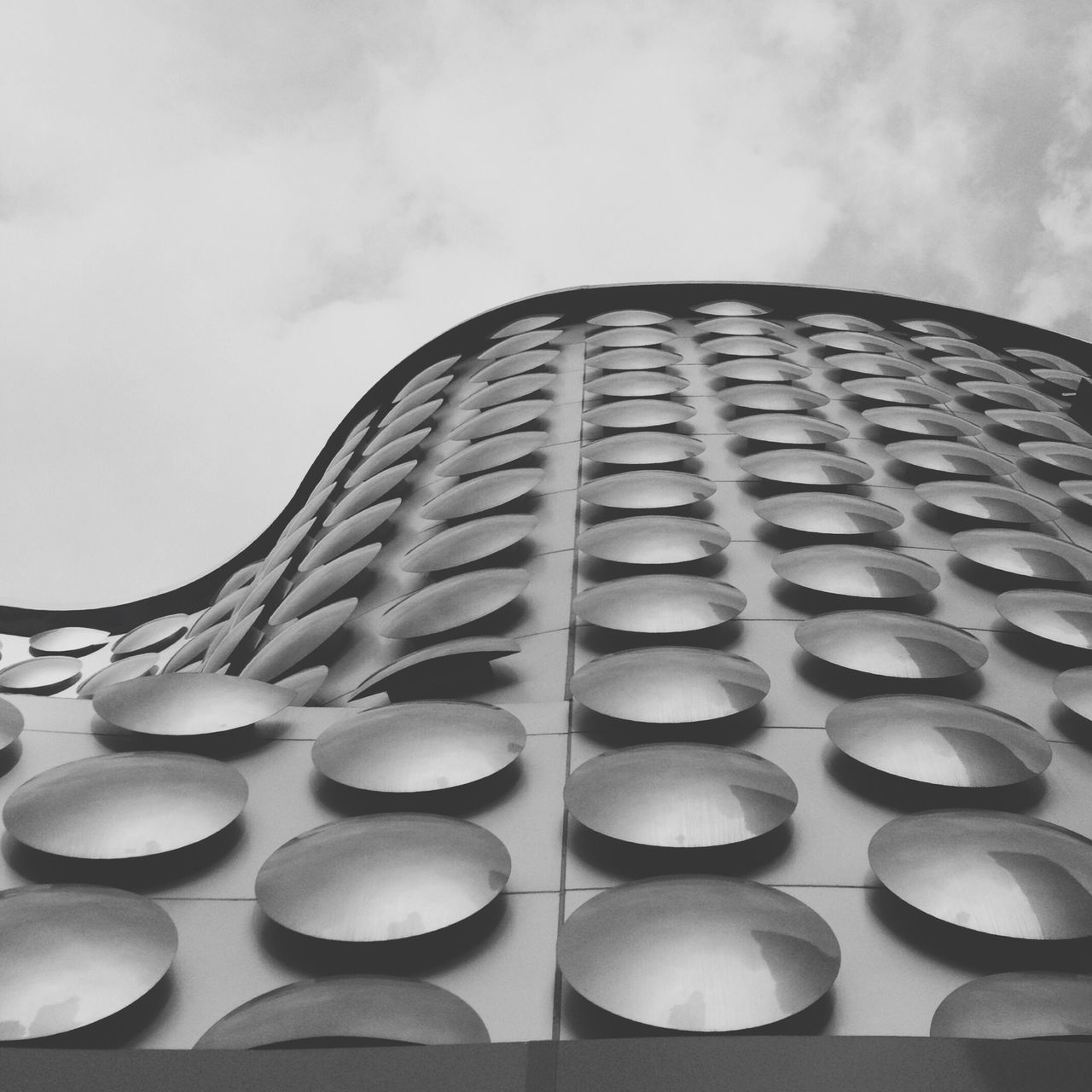 low angle view, architecture, built structure, sky, building exterior, pattern, modern, design, repetition, glass - material, architectural feature, building, window, no people, day, in a row, office building, shape, cloud - sky, geometric shape