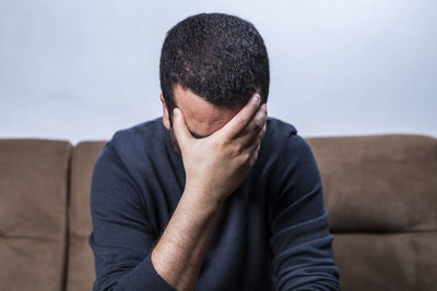 Midsection of man sitting on sofa at home