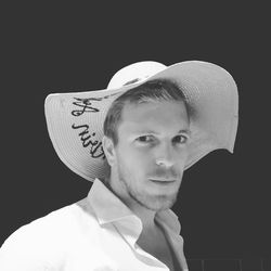 Portrait of young man wearing hat against black background