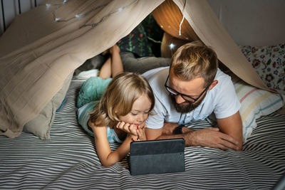 High angle view of boy using mobile phone while sitting on bed at home