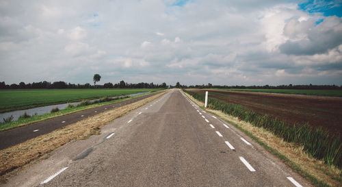 Empty country road against cloudy sky