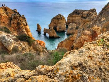 Scenic view of rocks on sea shore against sky