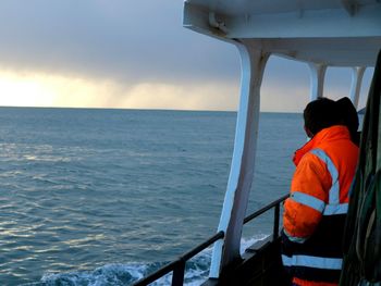 Rear view of man standing on boat sailing in sea