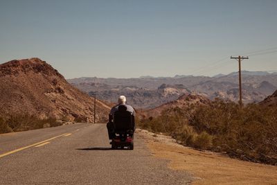 Rear view of man on road against mountain range