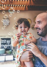 Smiling man carrying daughter