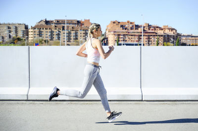 Young athlete exercising while running on footpath during sunny day