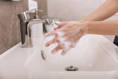 Cropped hand washing hands in sink