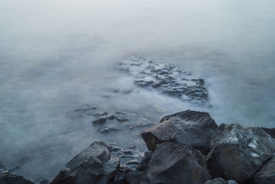 High angle view of rocky shore during foggy weather