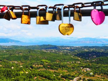 Padlocks hanging on mountain against sky