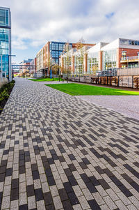 Footpath amidst buildings in city against sky