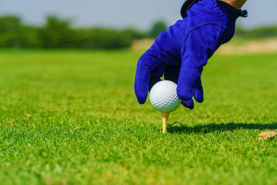 Hand golfer hold golf ball with tee ready to be shot at golf court.