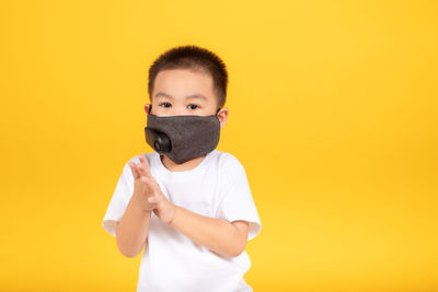 Portrait of boy standing against yellow background