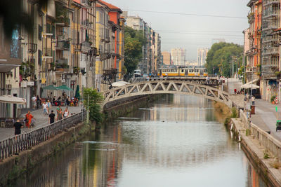 Footbridge over river in city against sky