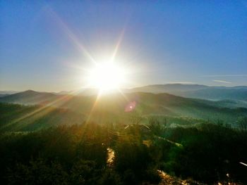 Sun shining through clouds over field