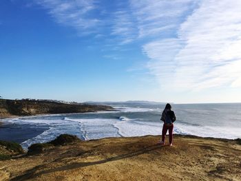 Full length of woman standing against sea and sky on sunny day